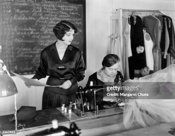American actress Gertrude Olmstead consulting one of the wardrobe staff at the MGM studios about a new dress that is being made for her.