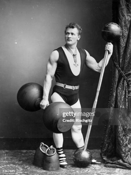 Eugene Sandow, performing strongman, with a selection of weights and dumbbells.