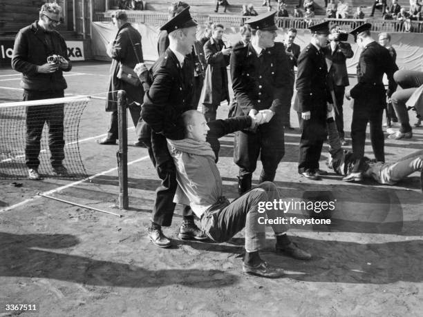 Man being arrested at an anti-apartheid demonstration in Oslo which involved sitting down on the tennis court to stop a Davis cup match against a...