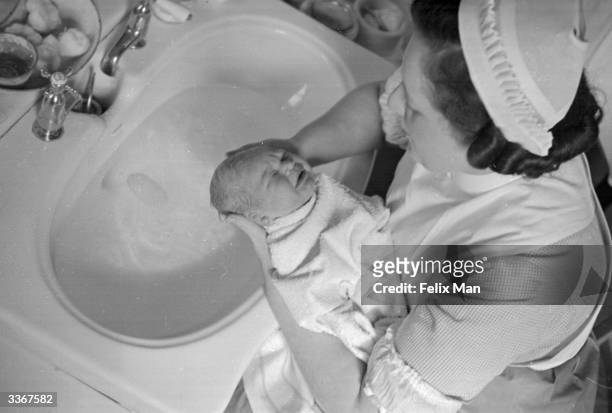 Nurse at the Royal Northern Hospital in London bathes a new-born baby boy. Original Publication: Picture Post - 39 - The Birth Of A Man - pub. 1938