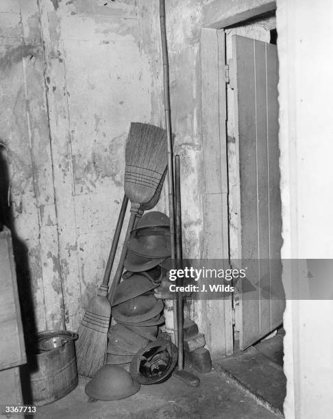 Tin hats, left over from the war lie still piled with brooms and a bucket in the corner of a Cellar in 10 Downing Street.