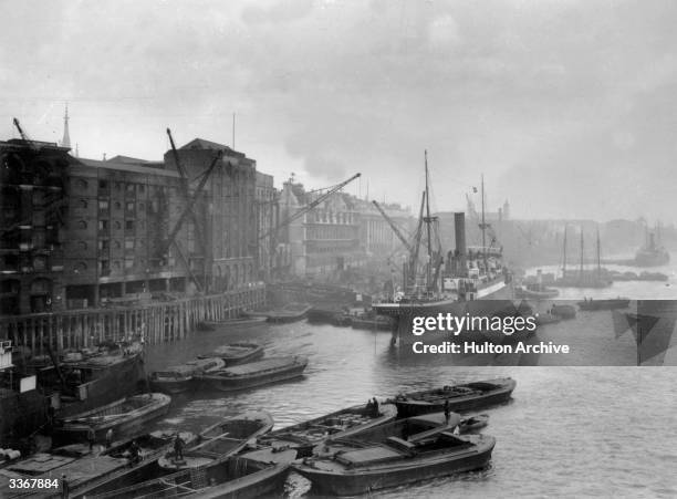 Waterfront warehouses and barges on the Thames in the docklands area of London.