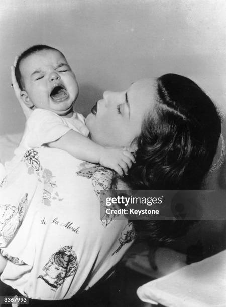 American actress Judy Garland holding her and film director Vincente Minnelii's daughter Liza, who later became famous in her own right as an actress...