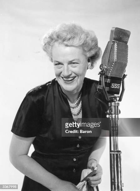 British singer and comedian Gracie Fields standing in front of a microphone.