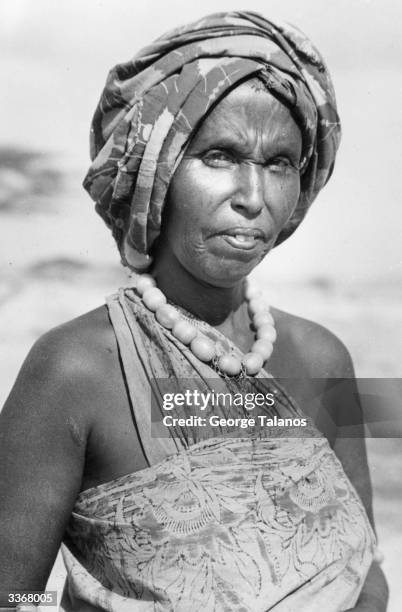 An Ethiopian woman wearing a patterned material dess and turban with a necklace made from wooden beads.