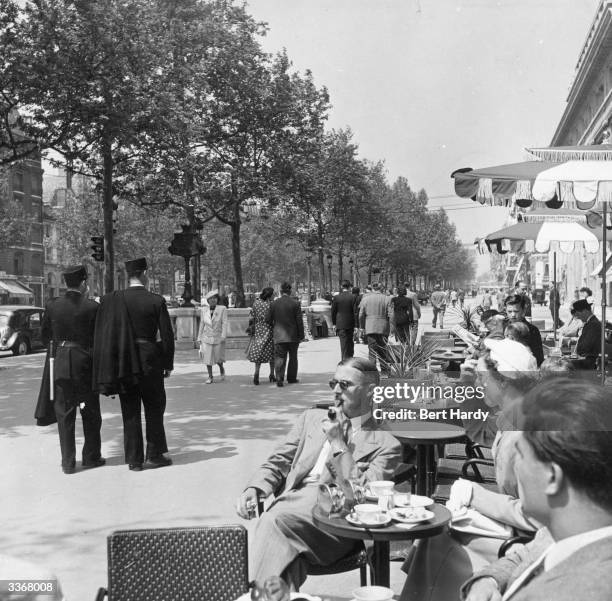 People relaxing at a pavement cafe and strolling down the Champs-Elysees on a Sunday morning in Paris. Original Publication: Picture Post - 5343 -...