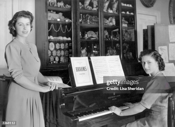 Princess Elizabeth and Princess Margaret Rose at a piano in the school room of Buckingham Palace, London.