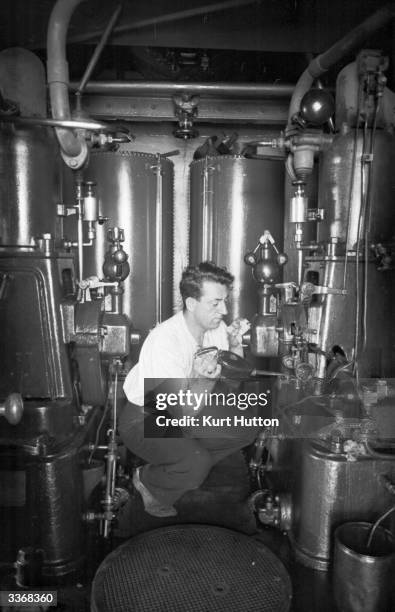 The operator of the Needles lighthouse, off the coast of the Isle of Wight oiling compression machinery used for a fog warning signal. Original...