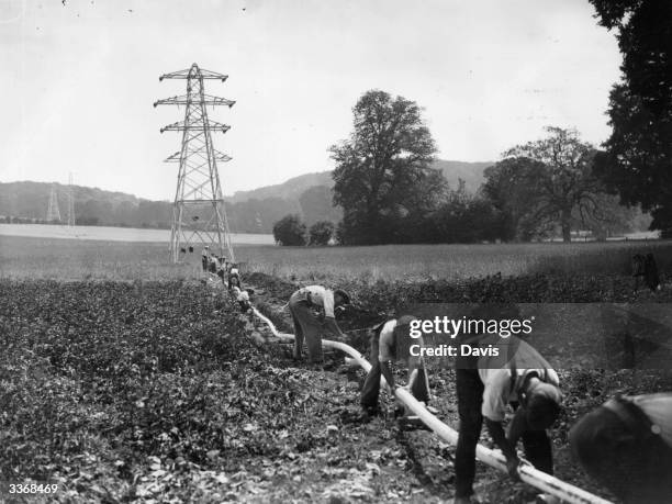 Workmen laying two 33,000 volt cables to connect the pylons either side of the 220 ft wide river at Mapledurham in Berkshire.