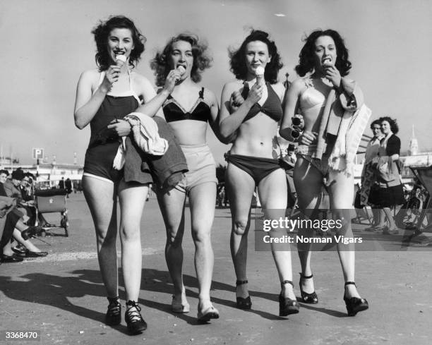 Four revue dancers strolling along the front at Southend on Sea in Essex dressed for the hot weather and ejoying an ice cream.