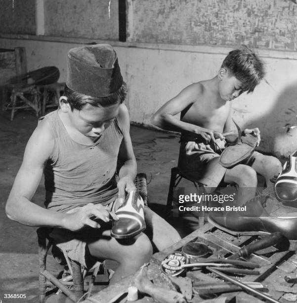 Two young Indonesian boys finishing shoes in a workshop.
