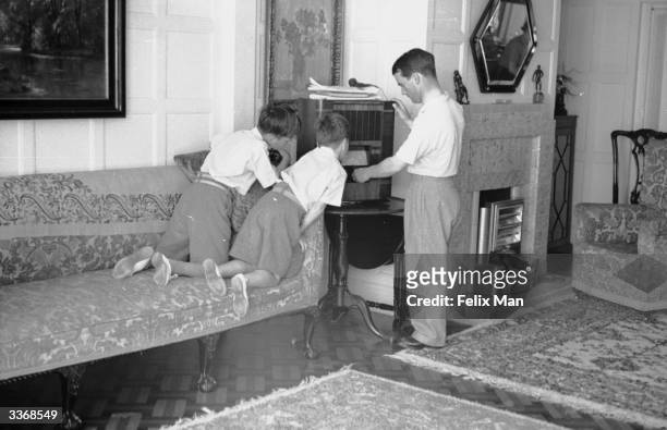 English jockey Gordon Richards listening to the radio at his home in Shoreham, West Sussex, with his sons Peter and Jackie. Original Publication:...