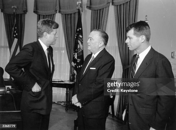 American President John F Kennedy at the White House with his brother Attorney General Robert Kennedy and head of the FBI J Edgar Hoover .