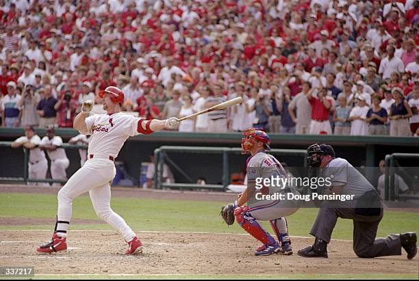 Mark McGwire of the St. Louis Cardinals hits his 70th home run of the season as catcher Michael Barrett of the Montreal Expos and umpire Rich Rieker...
