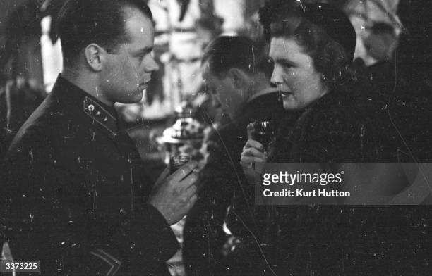 Mrs Pamela Churchill, wife of English journalist Randolph Churchill, talking to a Soviet soldier at the Soviet Embassy in London during celebrations...