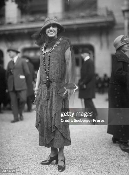 Dancer Mlle Rahna wears a dress designed by Lanvin. A cape sleeved dress with petal skirt, worn with a gauze scarf and a single rope of beads with a...