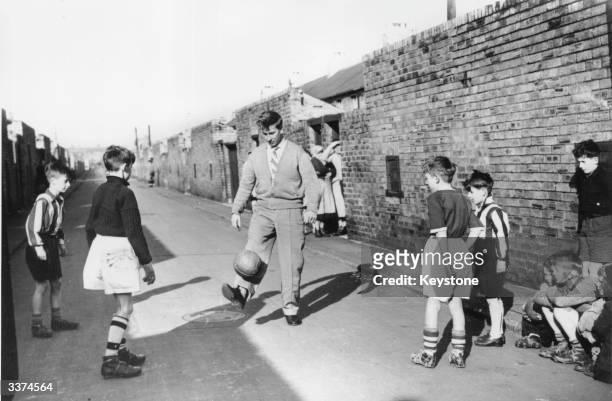 Footballer Bobby Charlton of Manchester United gets back into gentle training with some young fans in the backyard of his home on Beatrice Street,...