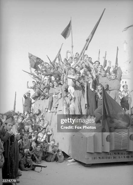 Militia men and women standing on a home made tank in Barcelona.