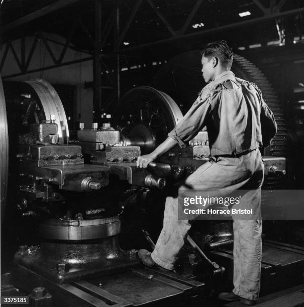 Factory worker calibrating train wheels with a machine.