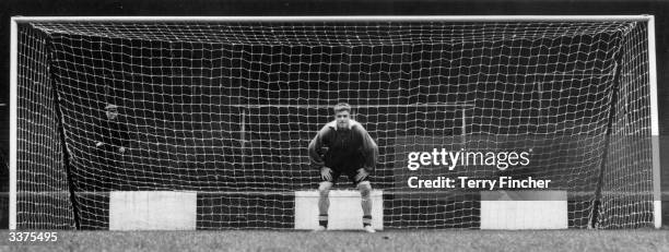 Charlton Athletic's goalkeeper, Sam Bartram, readies himself for the shots that will test out the new white plastic goal nets.