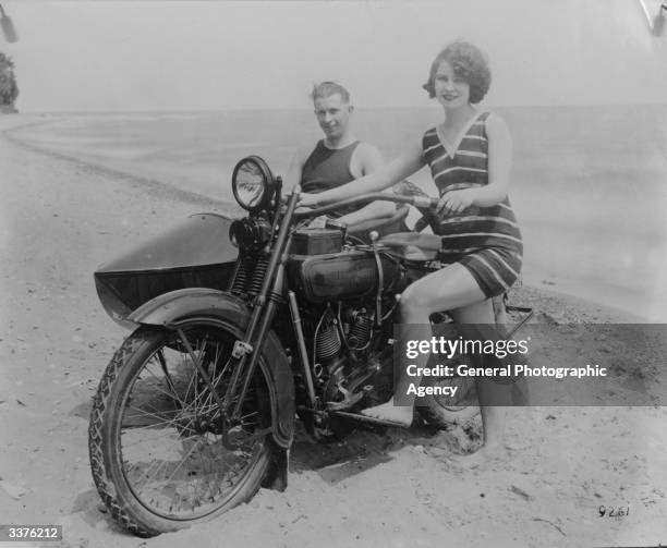 Woman on a beach in California with her Harley Davidson and boyfriend, who is sitting in the side car.