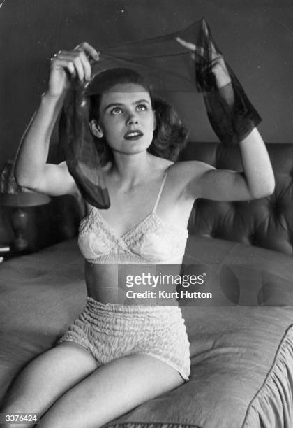 Woman in her underwear examining some nylon stockings. Original Publication: Picture Post - 4758 - Nylon For Lingerie - pub. 1949
