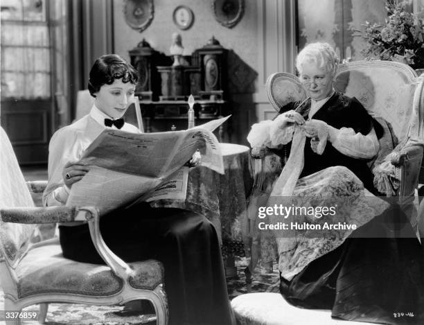 Austrian actress Luise Rainer sits reading a paper while her elderly companion works on her sewing, in a scene from Escapade' , directed by Robert Z...