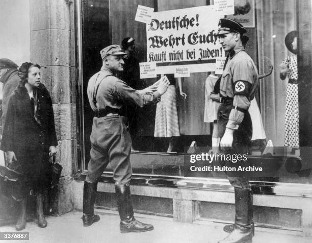 Members of the SA and SS in Berlin, pasting a notice onto a Jewish business, urging Germans to boycott Jewish shops.