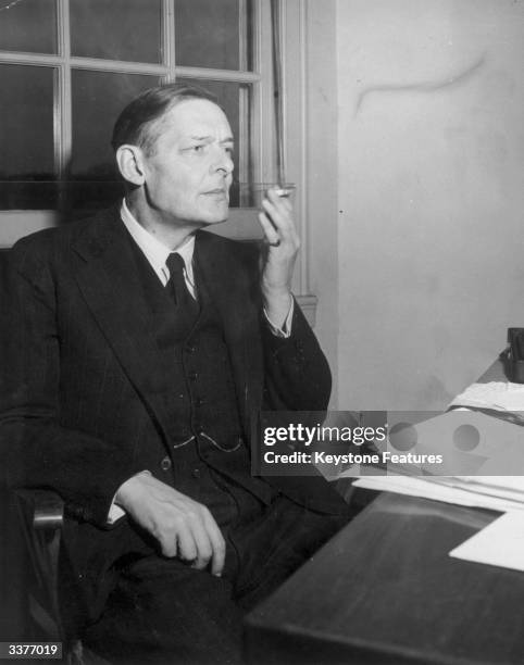 Writer TS Eliot takes a reflective puff at a cigarette before starting work.