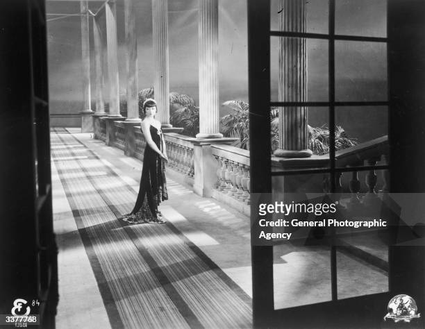 American-Chinese actress Anna May Wong beside a row of columns.
