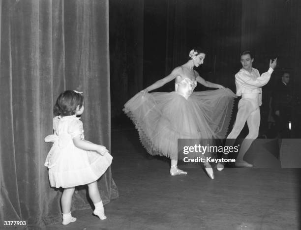 Behind the stage curtains, Susan, niece of the dancer Alicia Markova Asshe, imitates her aunt who is performing with Anton Dolin on stage.