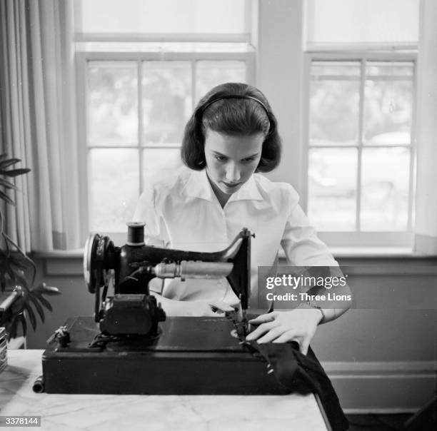 Teenage girl using a sewing machine in her home.
