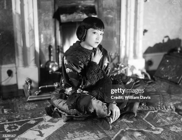 American-Chinese actress Anna May Wong sitting on the floor wearing a wrap.