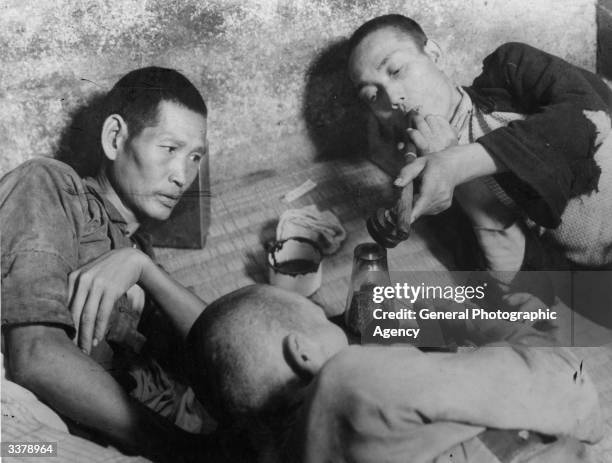 Three Chinese men smoking opium.