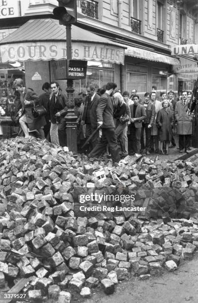 Parisians resume the business of everyday life, clambering over rubble left in the streets from the student riots.