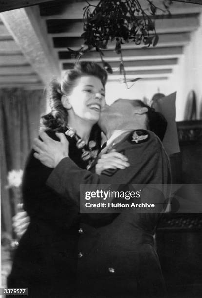 Couple kissing under mistletoe during a Christmas party for the Flying Fortress Boys.