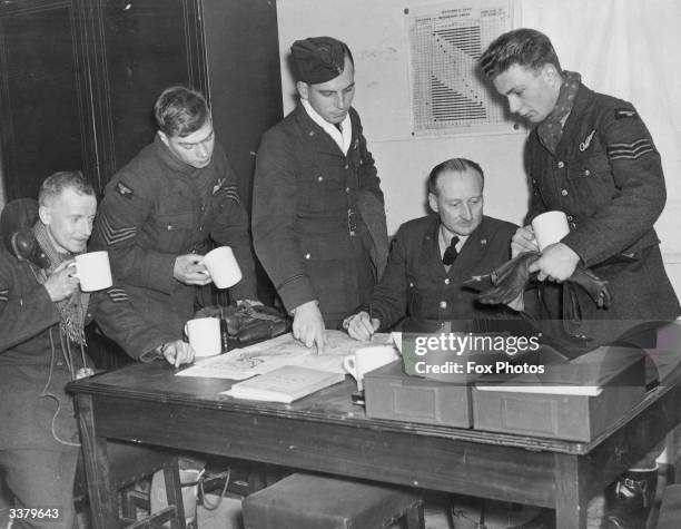 Whitely bomber crew reporting to an intelligence officer in the operations room after an operational flight. The VR on the officers' lapels show that...