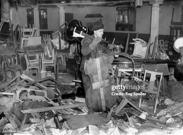 Man saves an intact guitar from amongst the wreckage of the Cafe de Paris in London, bombed during a World War II air raid.