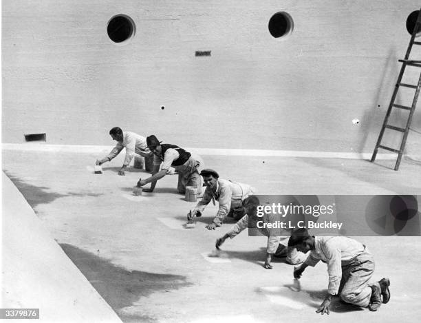 Painters start work on the 20,000 square feet of new concrete to complete the side and bottom of the new Empire Pool at Wembley, London, which is to...