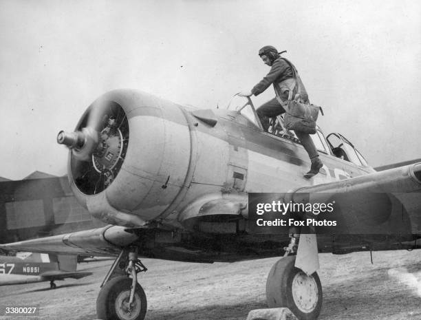 Trainee fighter pilot climbing into the cockpit of a Harvard aircraft for a training flight at a RAF station in England