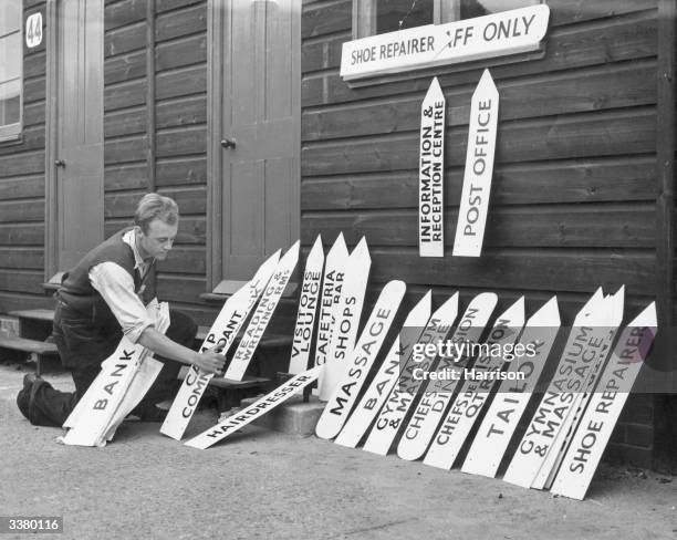 One of the workmen with some of the direction signs to be put up at the Olympic Centre in Richmond Park, Surrey. The 'village' will be home to 1,400...