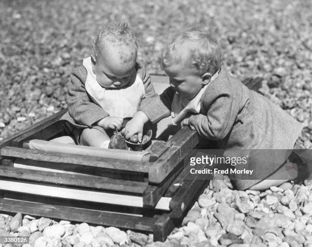 Month-old twins Stephen and Philip Udell playing on the beach at Worthing, Sussex.