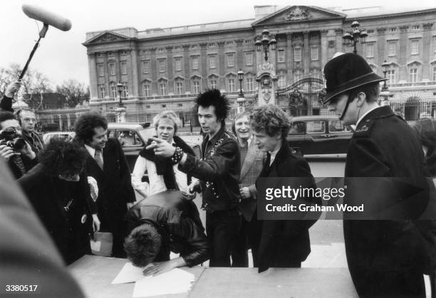 The Sex Pistols with their manager Malcolm McLaren signing a new contract with A&M Records, after being dropped from EMI, outside Buckingham Palace,...