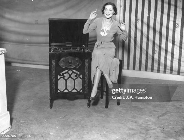 Woman demonstrating the Fullotone four-valve radio-gramophone at the Radio Olympia exhibition in London, the cheapest set at 16 guineas.