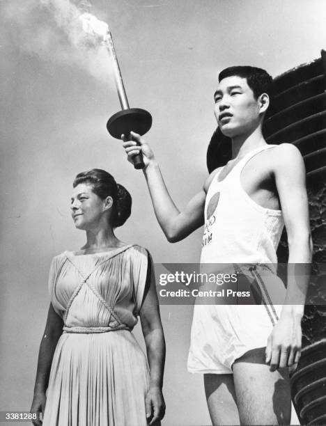 Yoshinori Sakai, born at Hiroshima on the day the first atomic bomb was dropped on the city, holding the Olympic torch beside Greek actress Aleka...