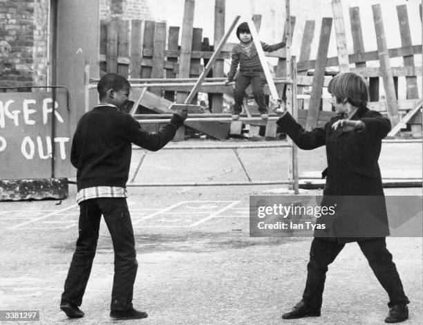 Two boys engaged in a wooden sword fight at the 'Make Children Happy' community centre in London's East End.
