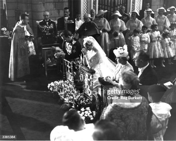 American actress Grace Kelly and Prince Rainier III of Monaco praying during their wedding ceremony at Monaco Cathedral.