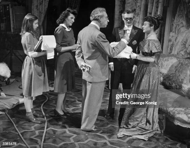 Script girls stand by as Hungarian-born British film director and producer Alexander Korda explains the next sequence to Paulette Goddard and Hugh...