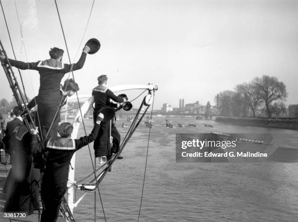 Cadets on board the training ship 'Stork' cheer as the Cambridge University rowing team lead Oxford by three lengths during the University Boat Race...