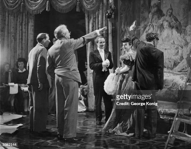 Hungarian-born British film director and producer Alexander Korda explains the next sequence to Paulette Goddard during the filming of Oscar Wilde's...